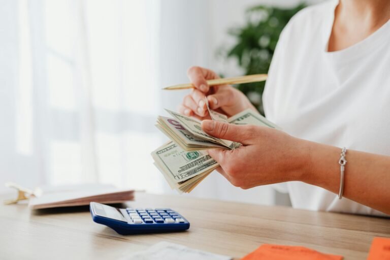 Close-up of a woman holding US dollars, calculating finances at home.